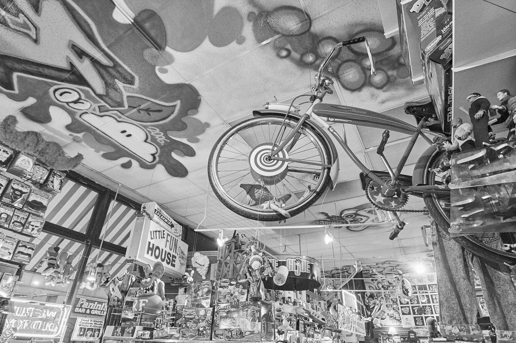 A store with a themed wall painting featuring vintage bicycle designs and a real bicycle positioned in the center of the store.