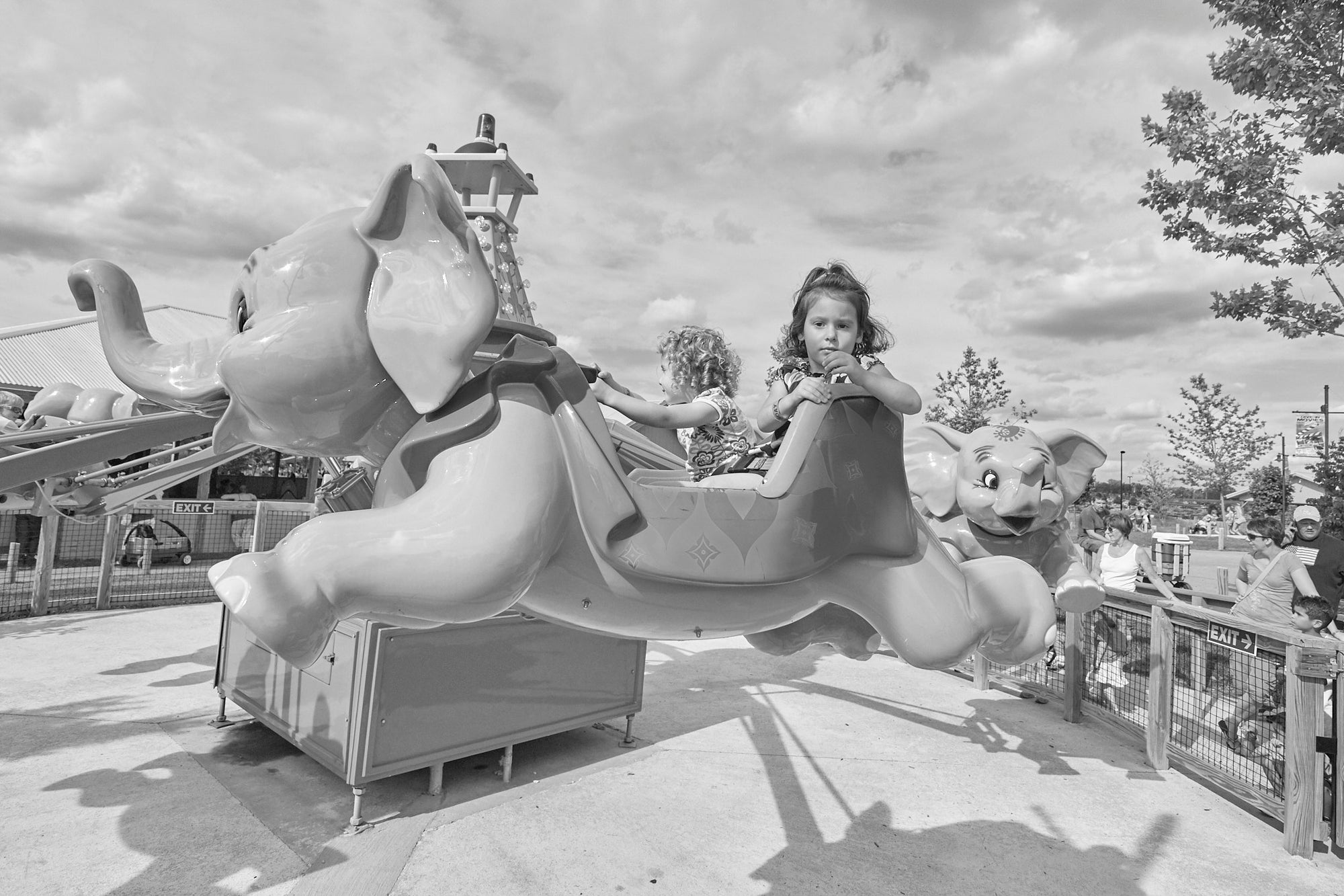 A child riding an elephant-shaped carnival ride, with the ride's platform and surrounding area visible.