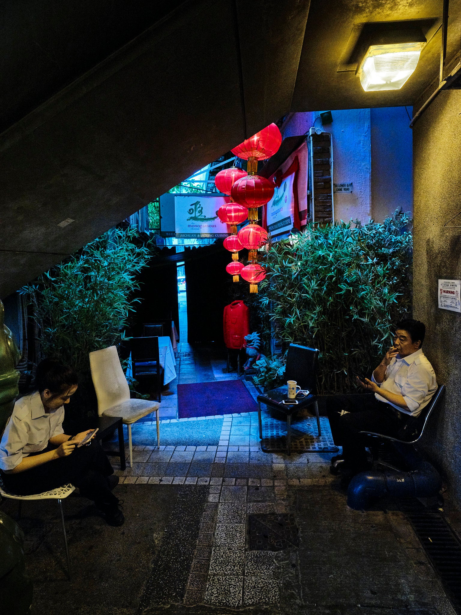 Outdoor seating area with patrons, featuring red lanterns and a cozy atmosphere.