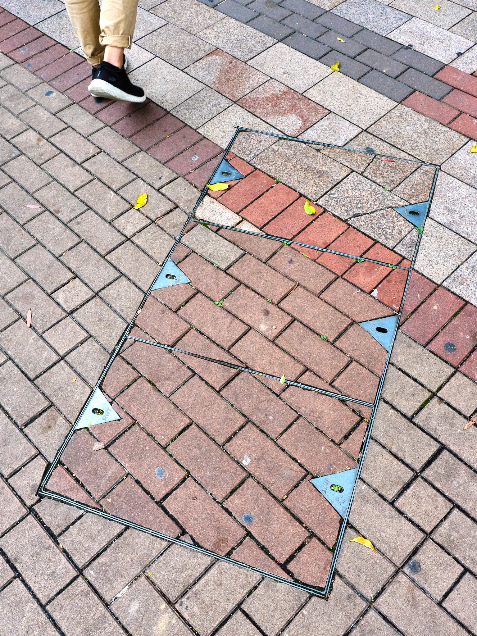 A metal access frame placed on a brick pathway, with feet walking on it.