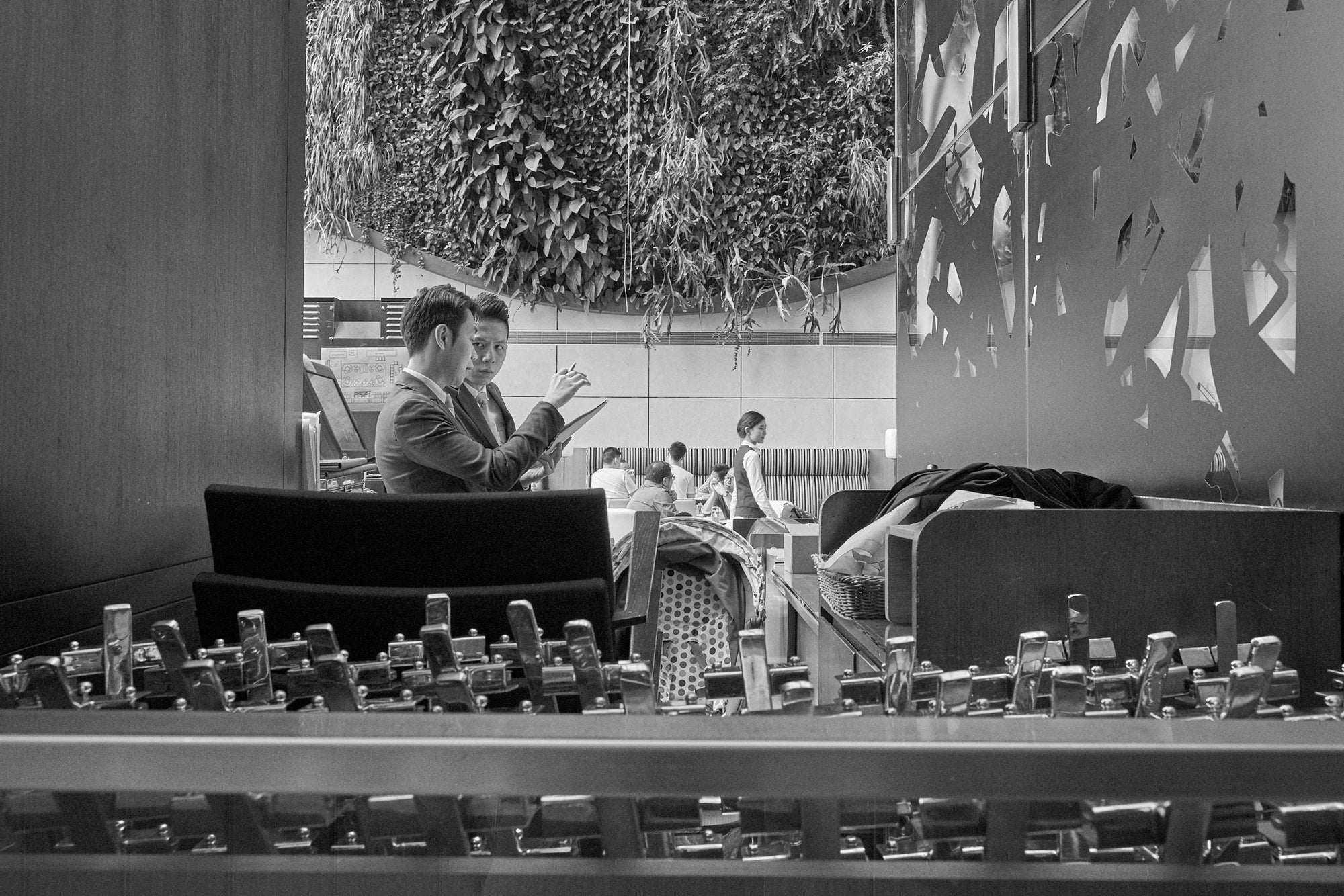 Black and white photograph of the Hotel  lobby in Hong Kong featuring two men discussing operations.