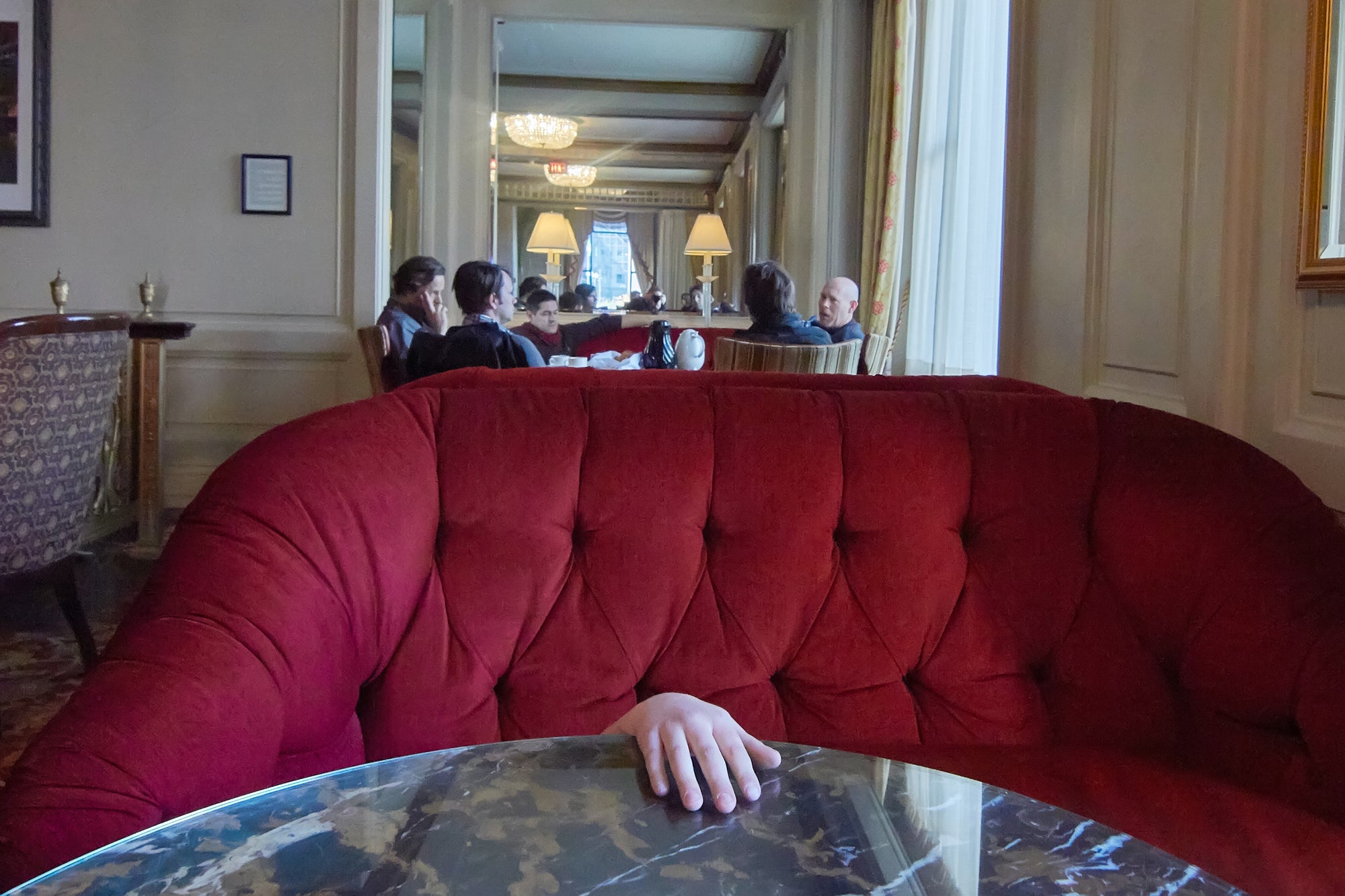 A photo depicting a semi-private club setting with a prominent red couch and several people seated in the background.