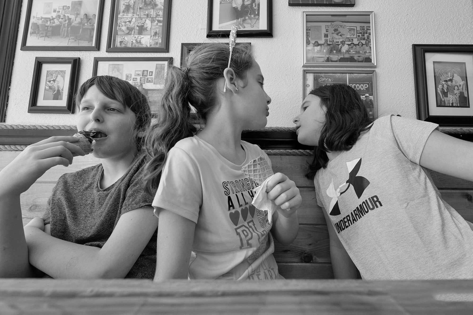 A black and white photograph of three young people, seated in a booth, having an animated discussion.